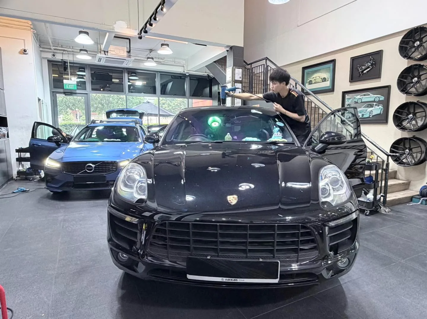 A black Porsche SUV with its doors open during window tinting work.