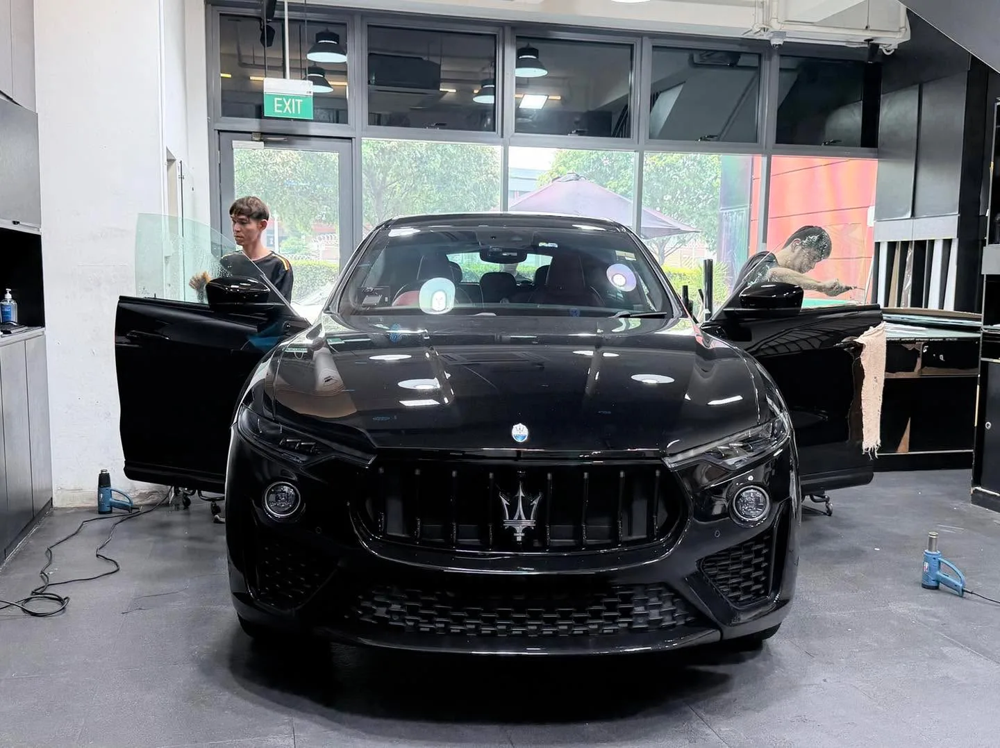 A black Maserati SUV with doors open inside the workshop.