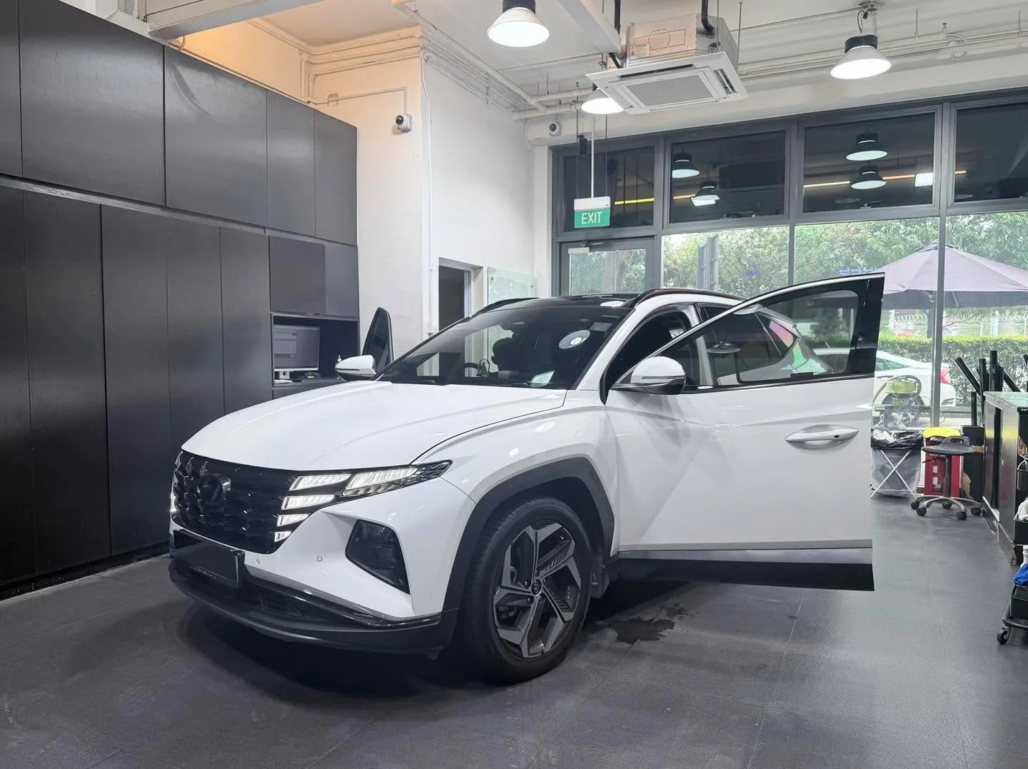 A white Hyundai SUV with driver door open in the workshop.