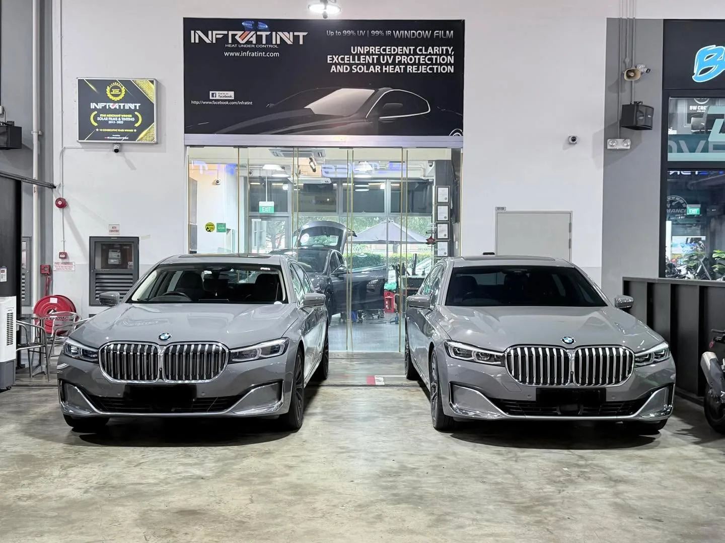Two grey BMW 740 sedans parked at the workshop entrance.