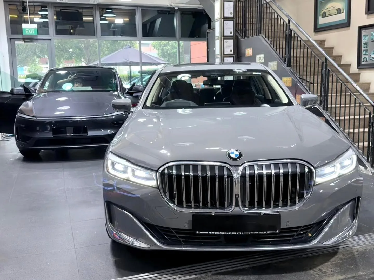 A grey BMW 740 sedan head-on at the workshop, with distinctive vertical grille.