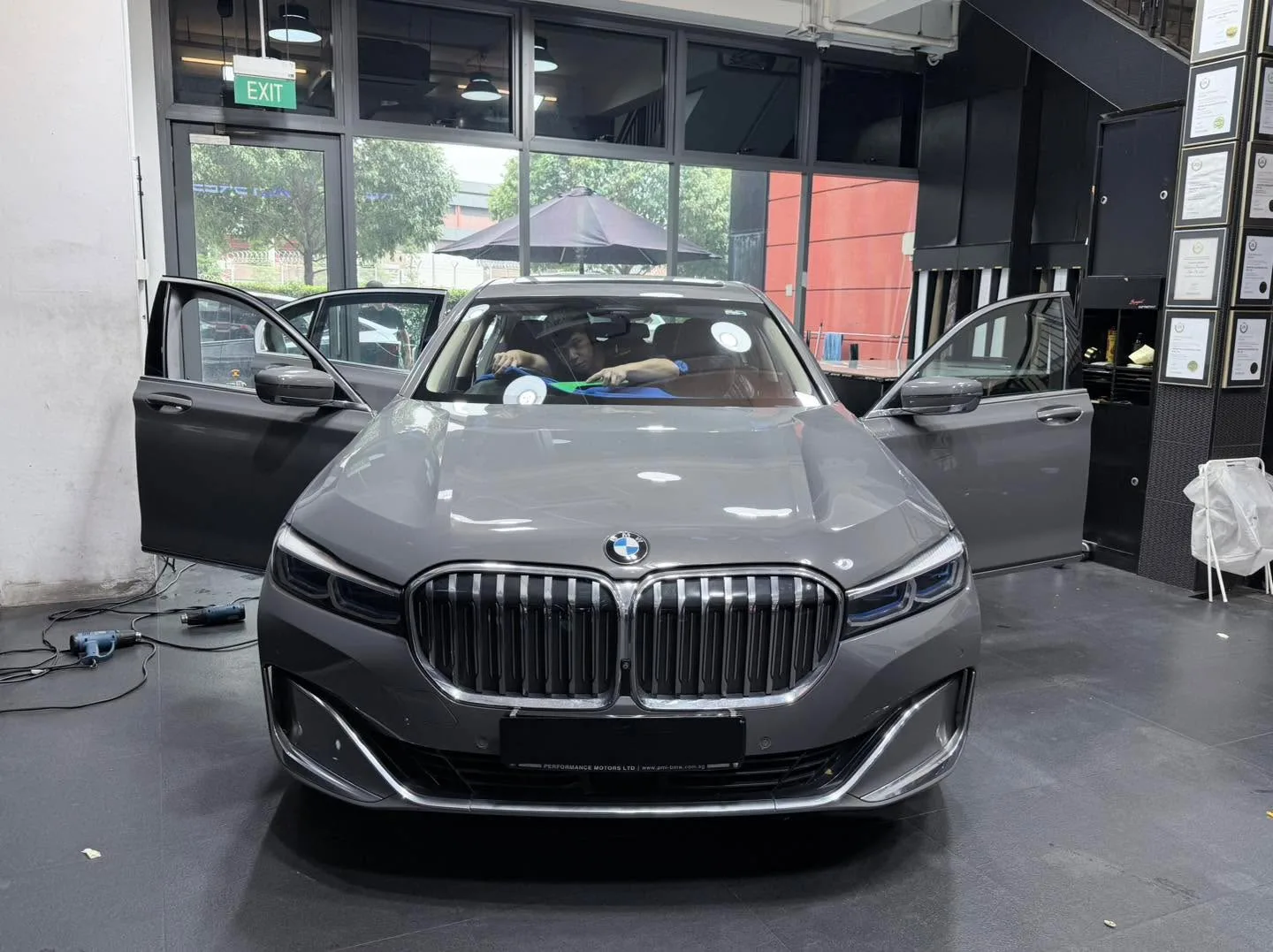 A grey BMW 740 sedan with both doors open during tinting application.