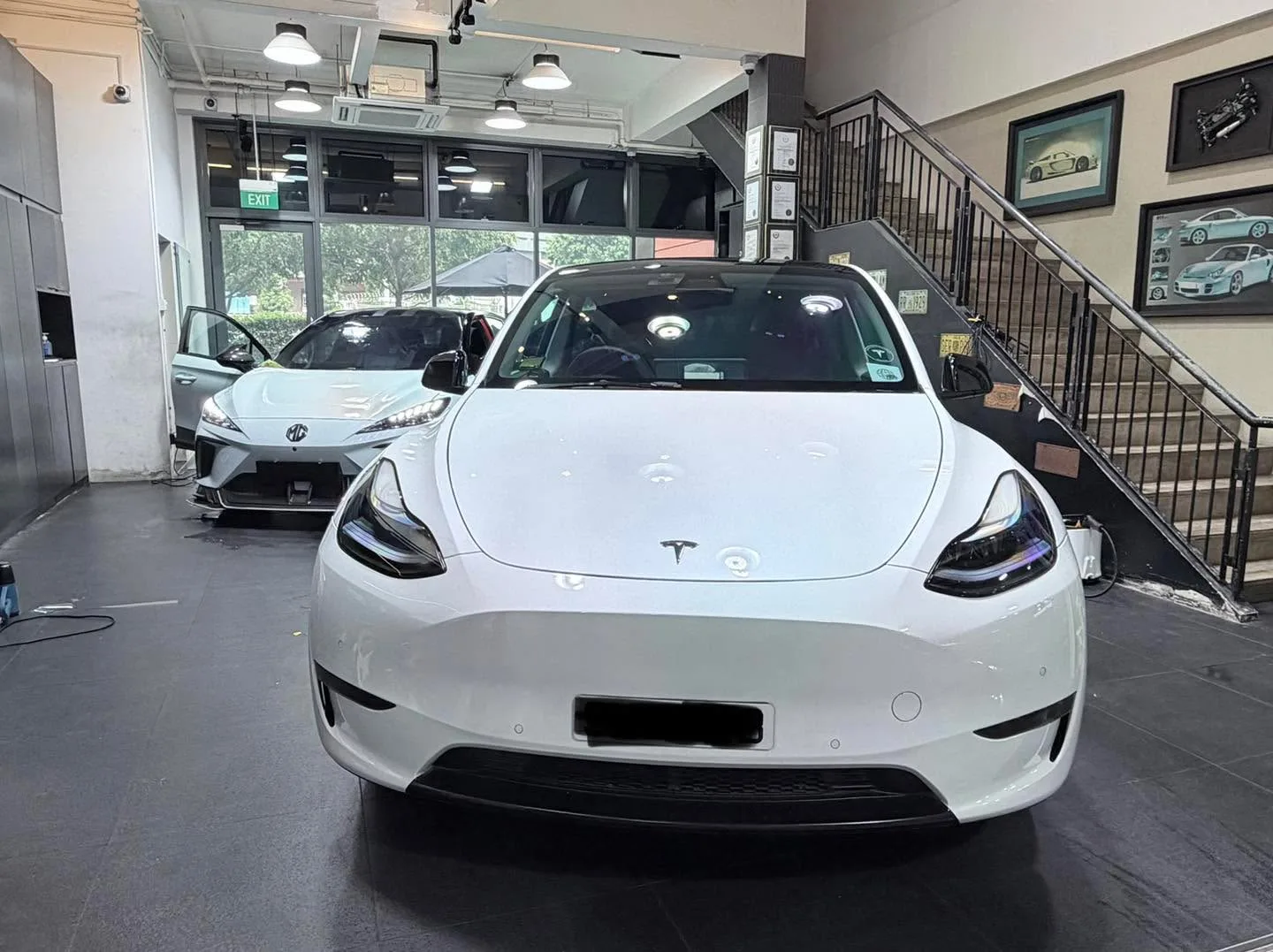 A white Tesla Model Y sedan and a white MG 4 hatchback in the facility.
