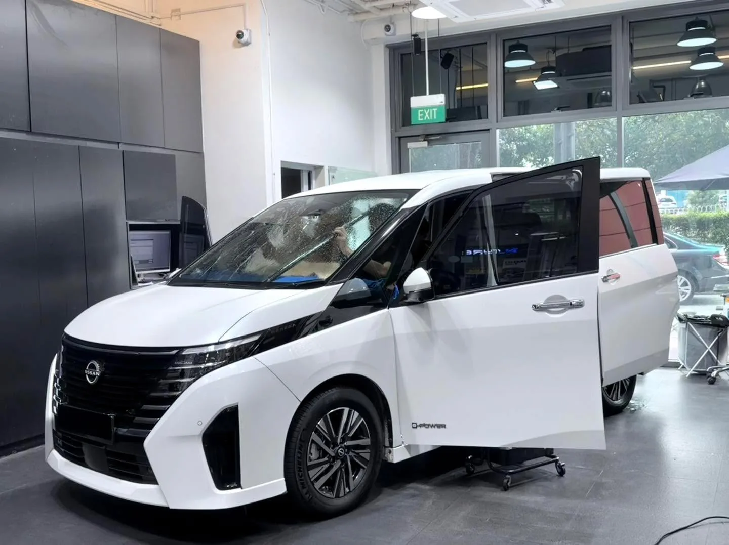 A white Nissan Serena minivan stands in the workshop with one door open.