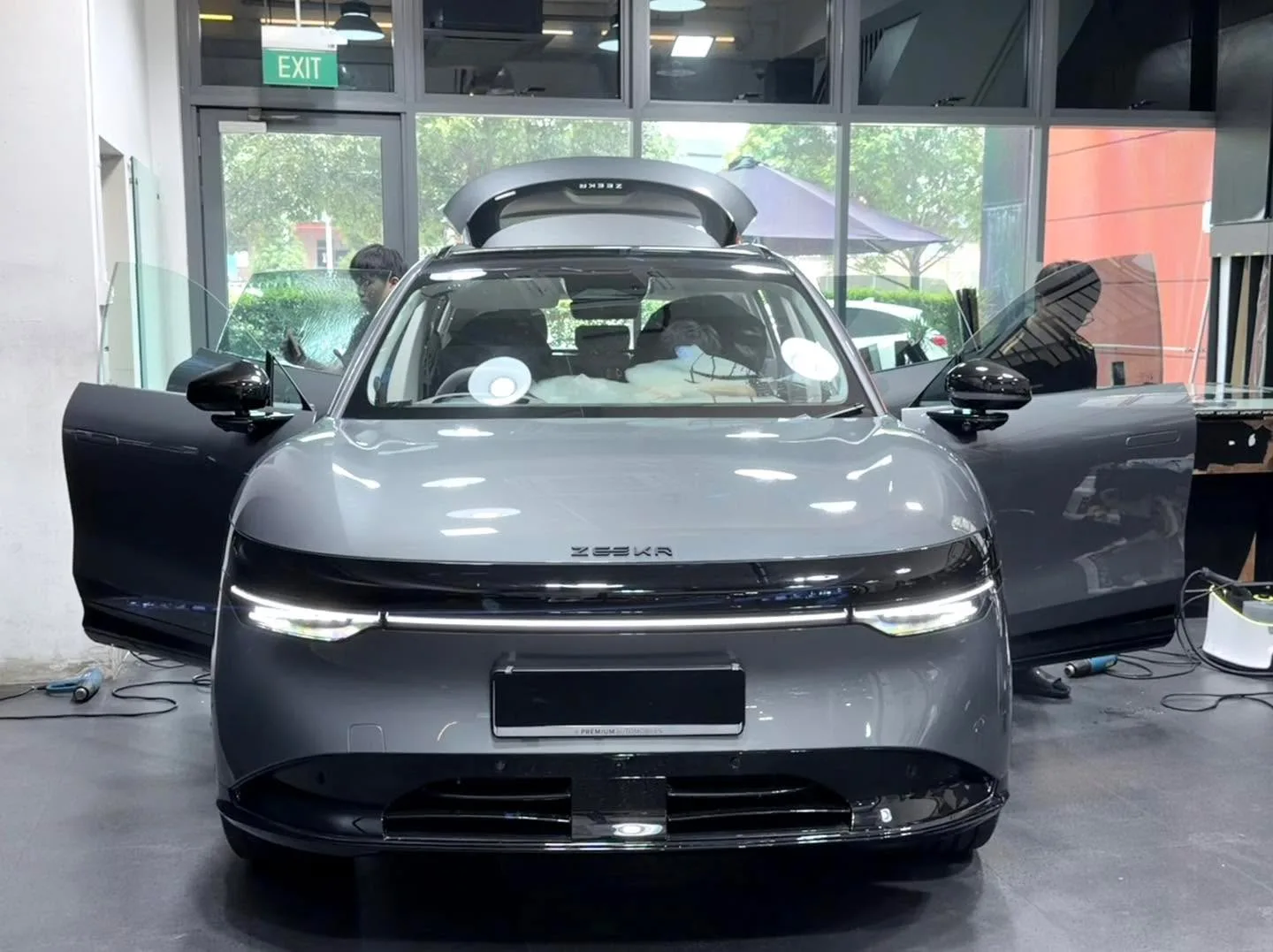 A silver SUV with gullwing doors open, viewed from the front.