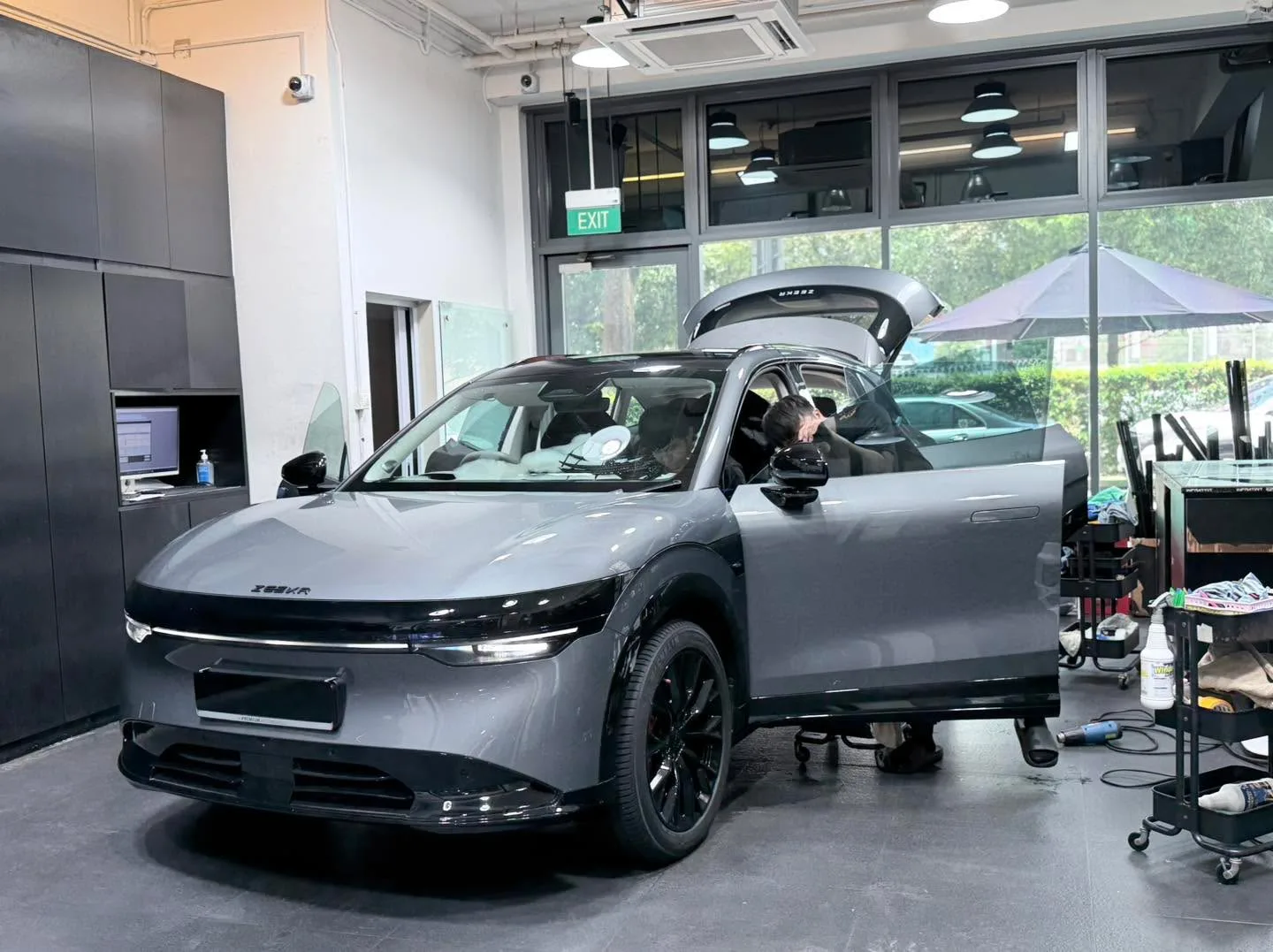 A silver SUV with gullwing door open, positioned sideways in the workshop.