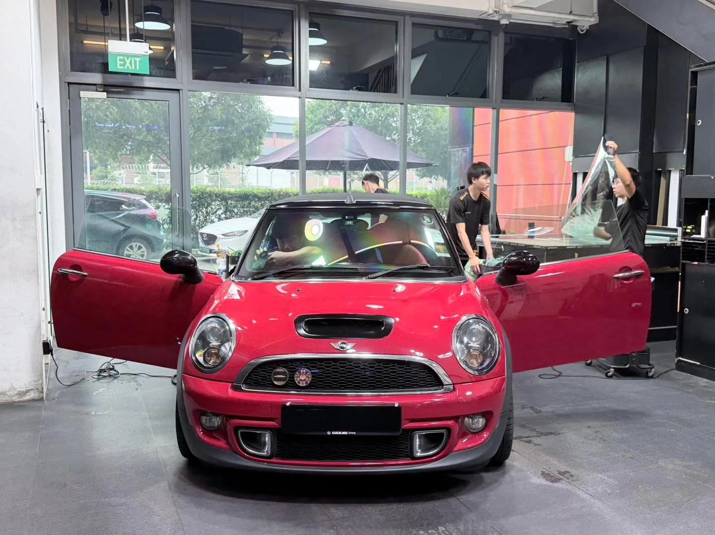 A white coupe with black details and open door in the workshop.