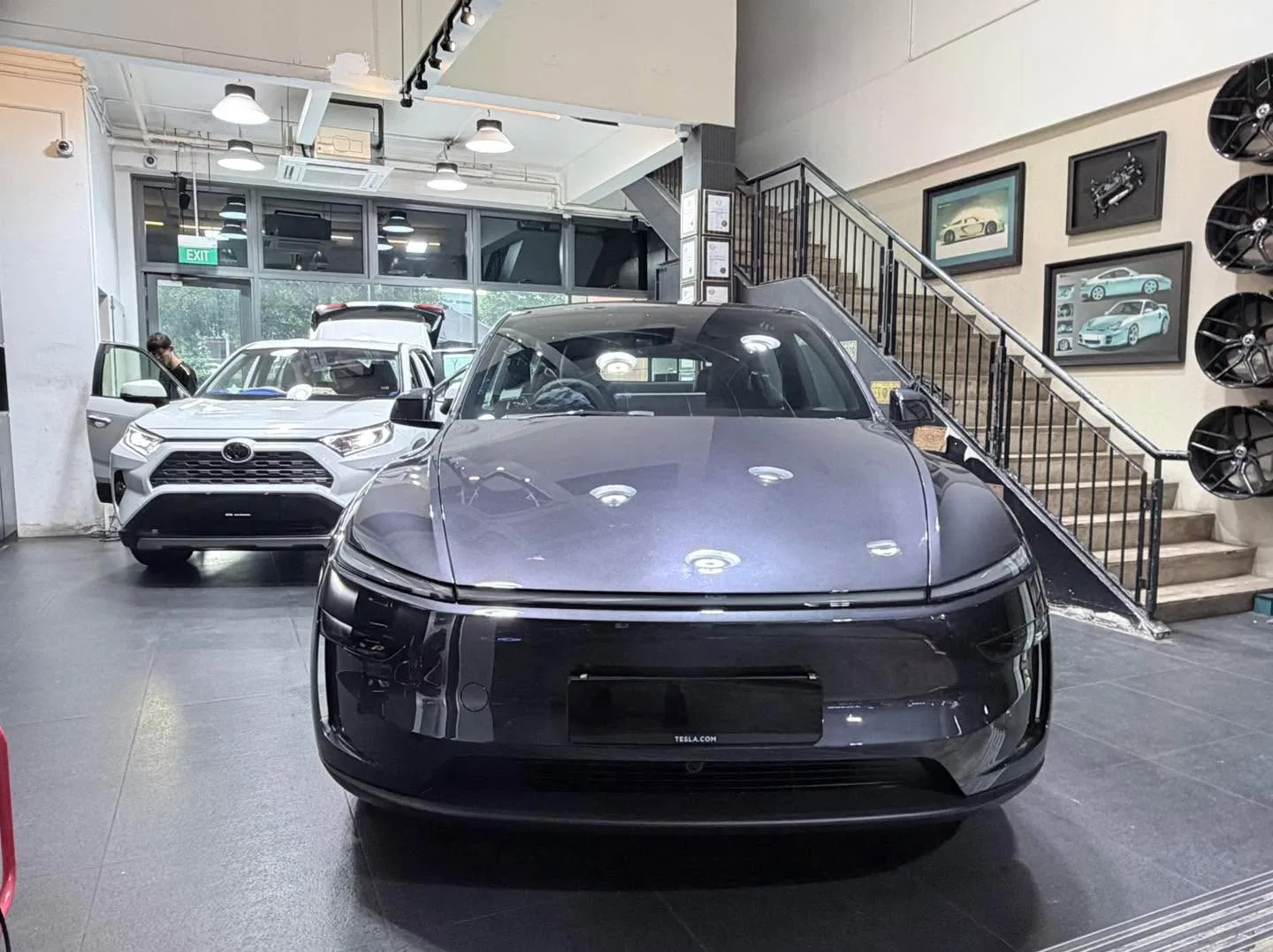 Three cars parked in a modern showroom. Centre-right: white BMW i5 Touring sedan.
