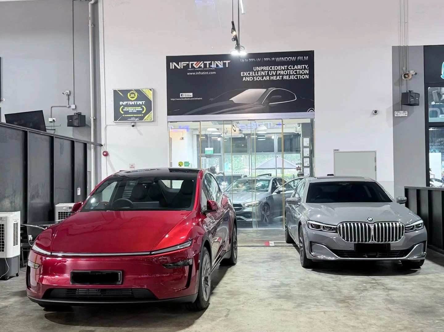 A red electric car and a silver BMW SUV inside the workshop.
