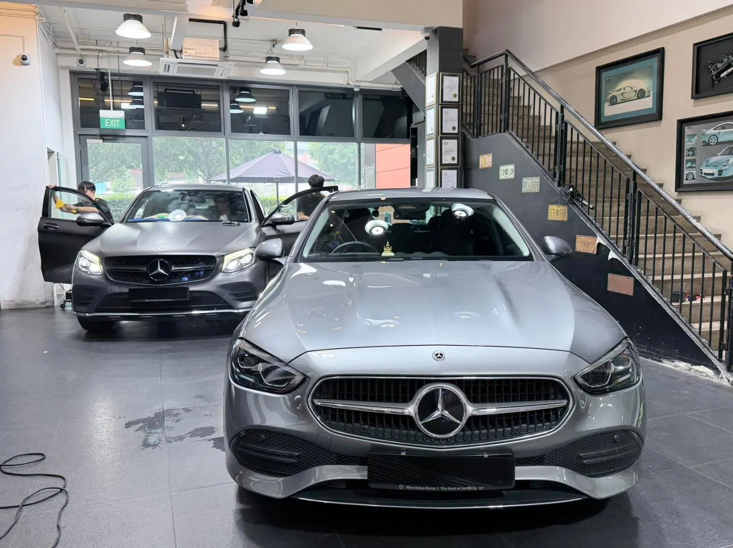 A dark Mazda sports car and a dark sedan inside the workshop.