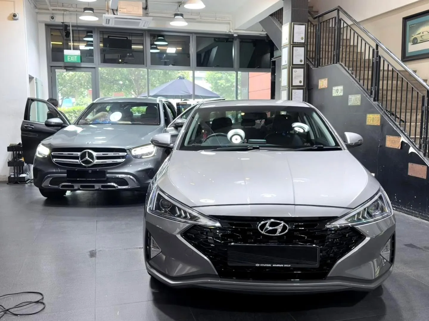 A white BMW X3 SUV and a silver Hyundai sedan parked inside the workshop.