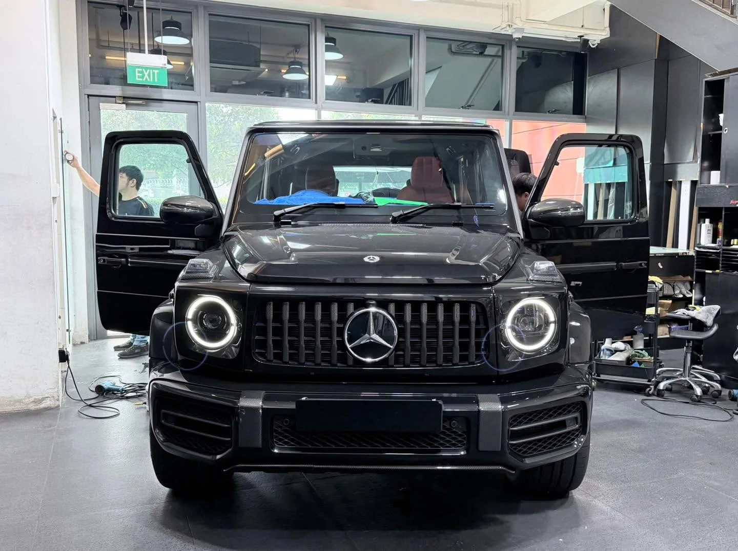 A black Mercedes-Benz G63 SUV with the door open, undergoing window tinting.