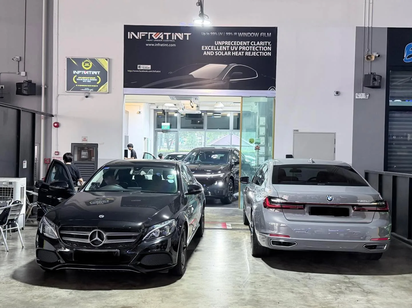 A black Mercedes-Benz C-Class sedan parked indoors next to a silver sedan.