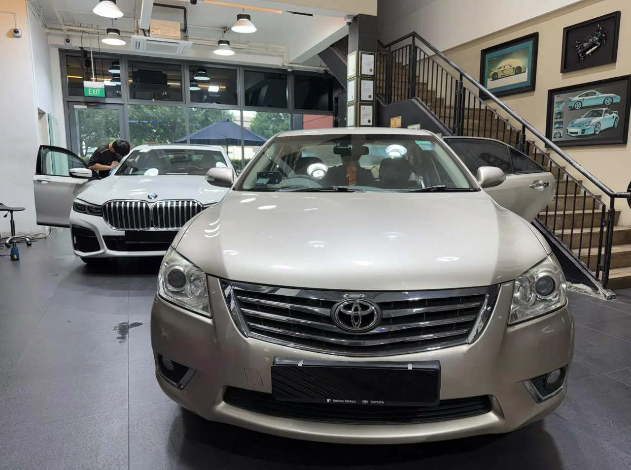 A beige Toyota Camry sedan facing forward, with a white BMW saloon visible in the background.