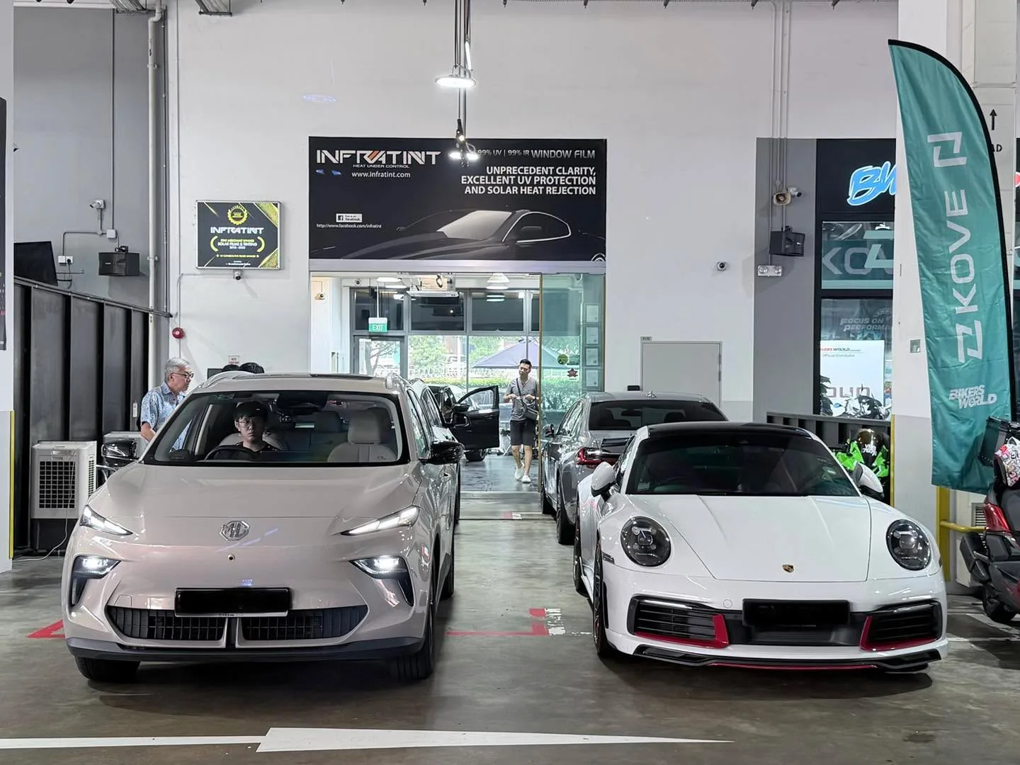 A beige saloon and a white sports car parked in the workshop.