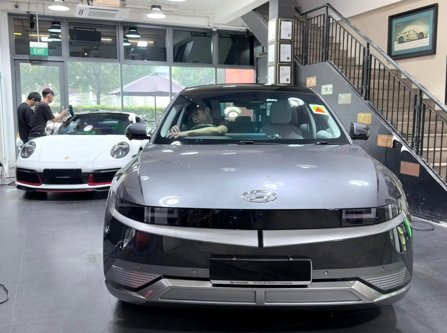 A silver Hyundai Ioniq 5 SUV parked indoors with staff nearby.