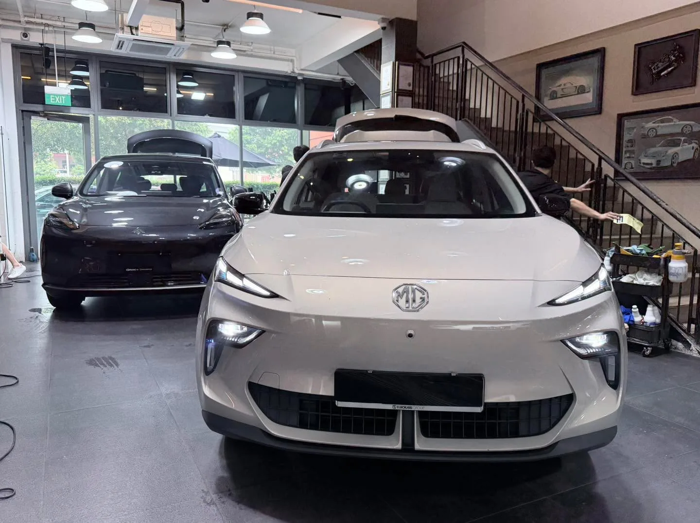 A silver MG S5 SUV and dark saloon parked indoors.