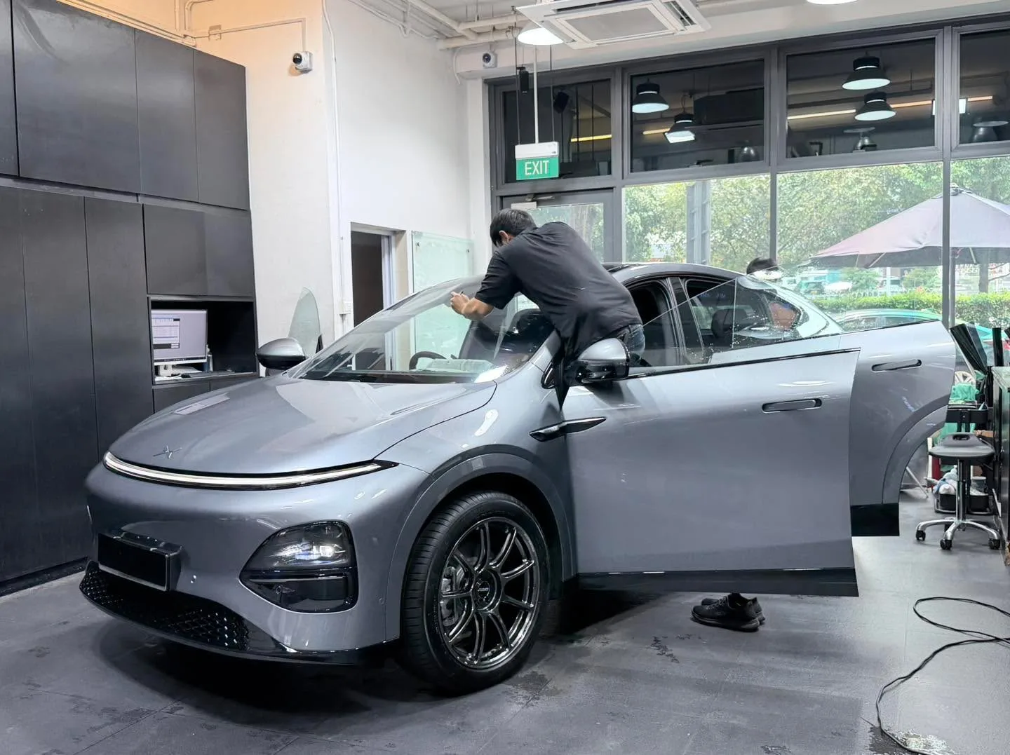 A silver compact electric SUV with doors open during window tinting work.