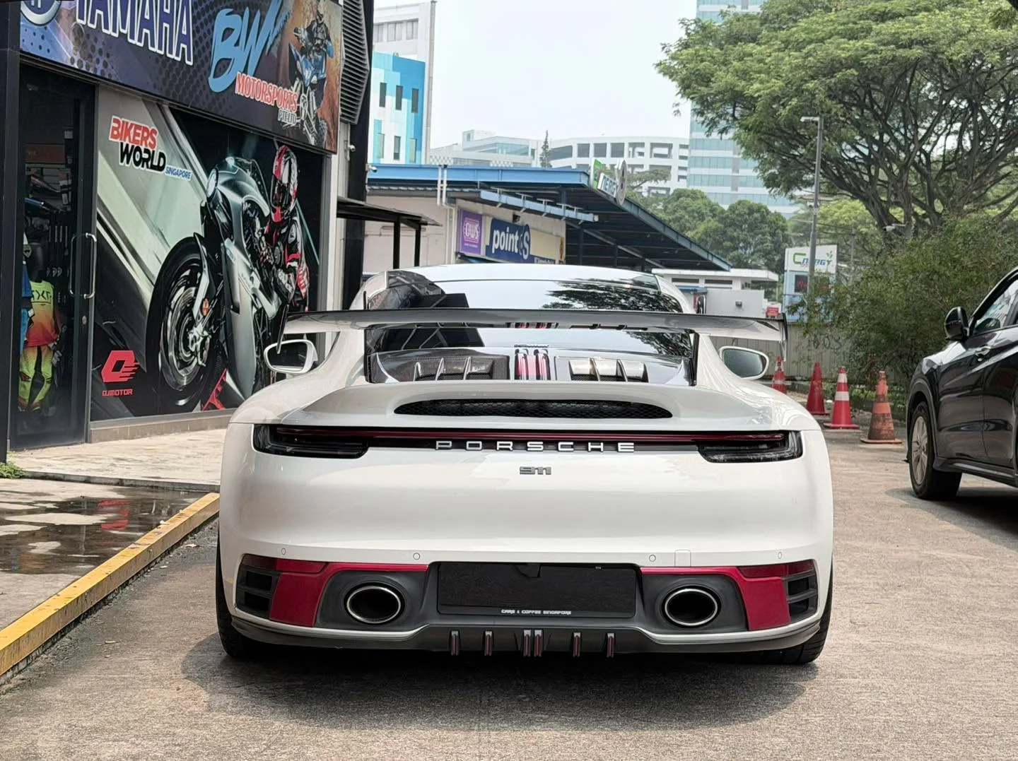 Rear view of a white Porsche sports car with distinctive red tail lights and dual exhaust ports.