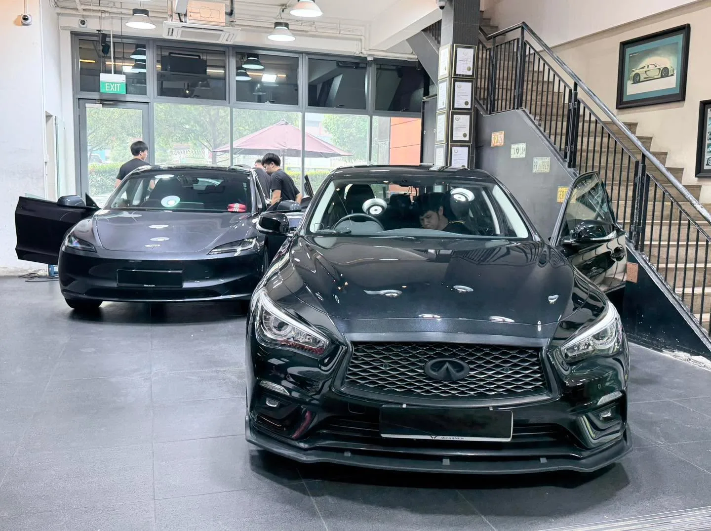 A black Infiniti Q50 in the foreground with its driver door open, and a grey Avatr partially visible to the left.
