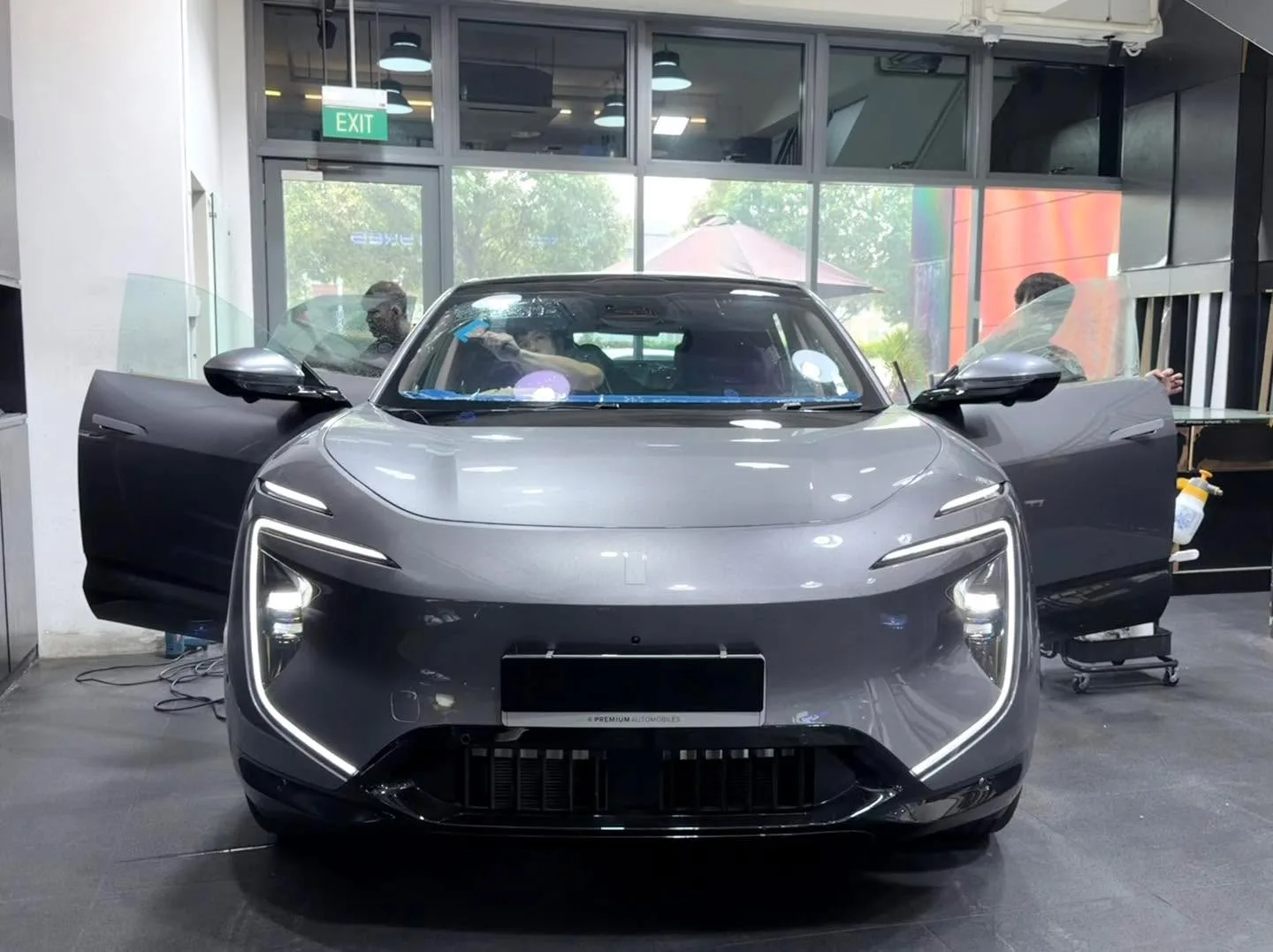 A grey Avatr 07 SUV facing forward with both doors open, parked indoors with technicians visible.