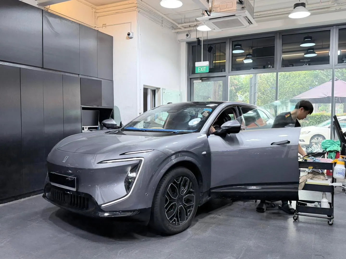 A grey Avatr 07 SUV with doors open, being tinted indoors at the workshop.
