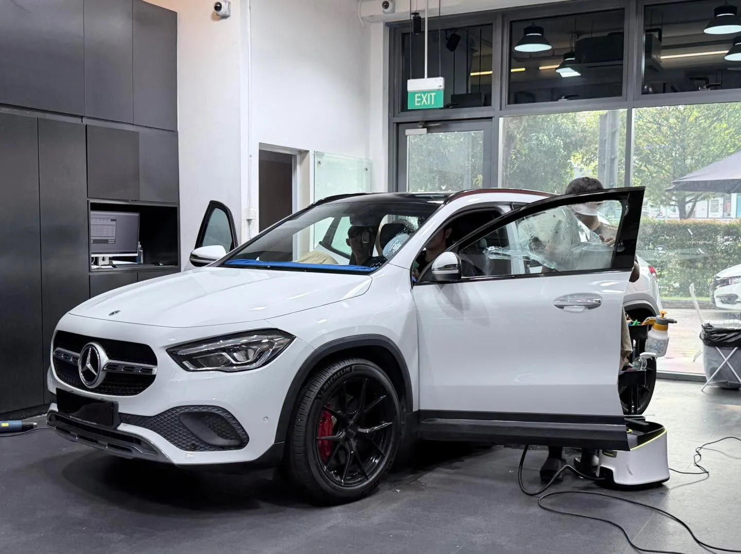 A white Mercedes-Benz SUV with doors open and a technician working on the window tint.