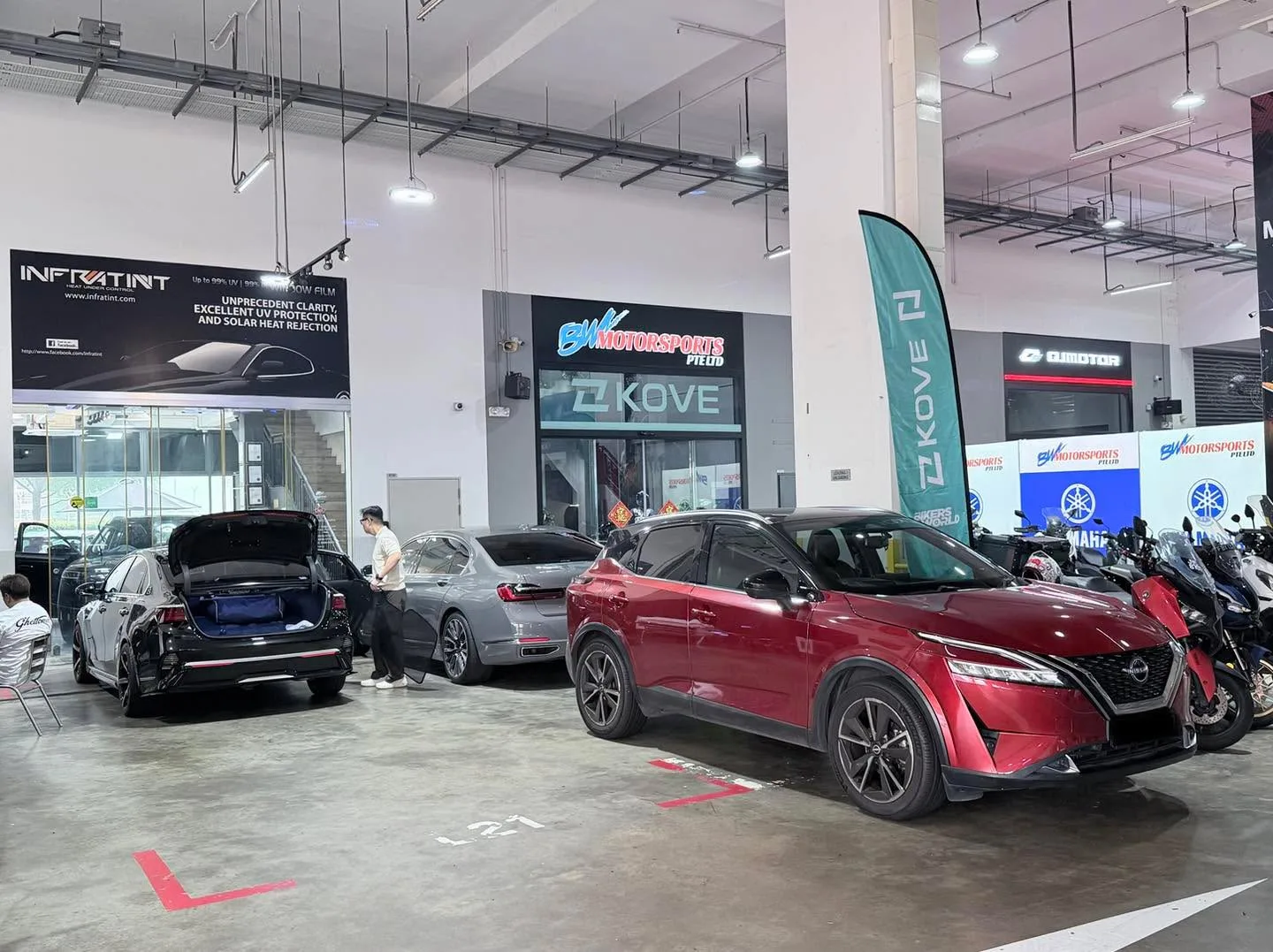 Black Kia Cerato, white Mercedes-Benz, and red Nissan Qashqai in workshop.