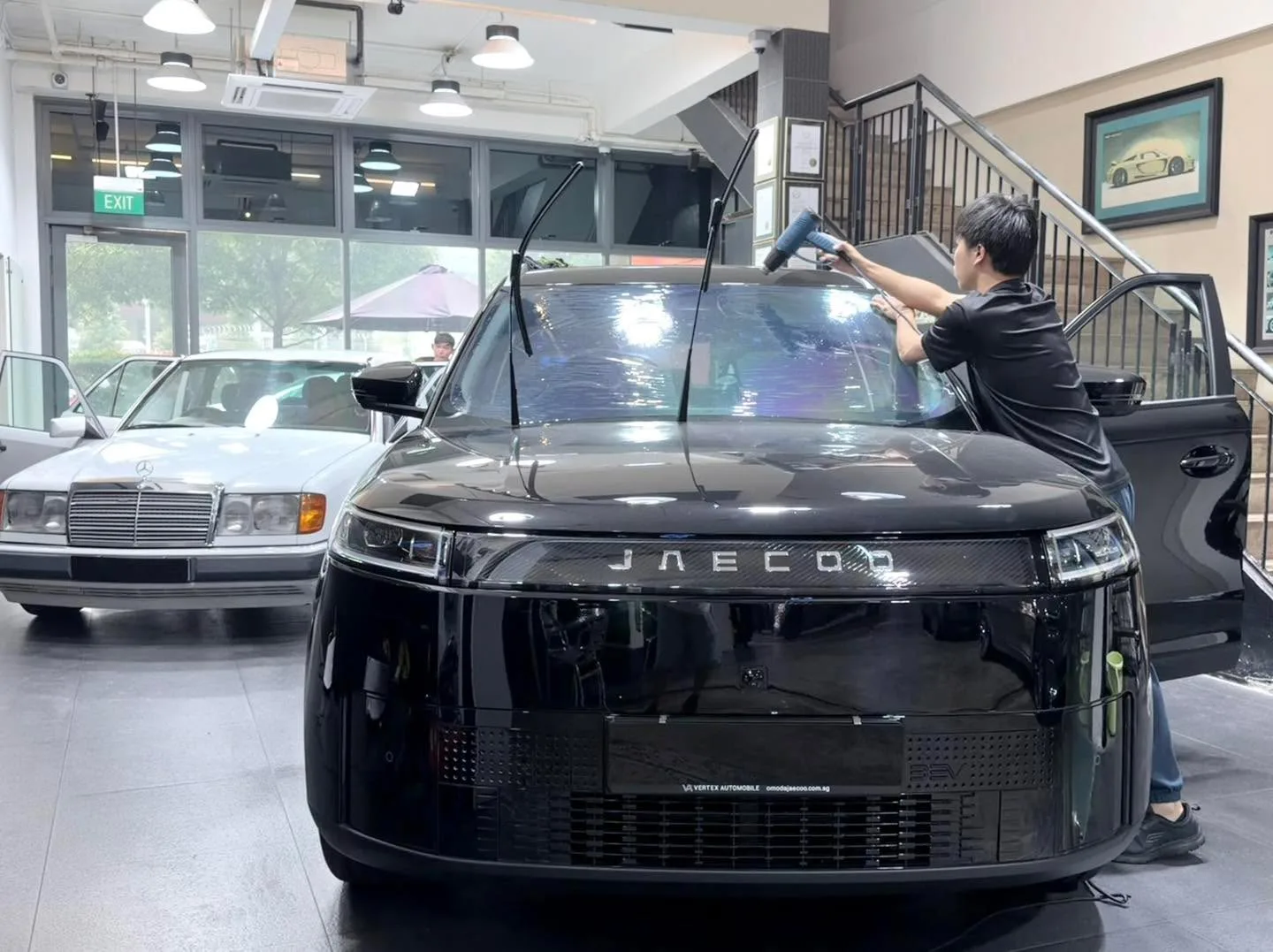 Black Honda HR-V with doors open, technician applying tint inside.