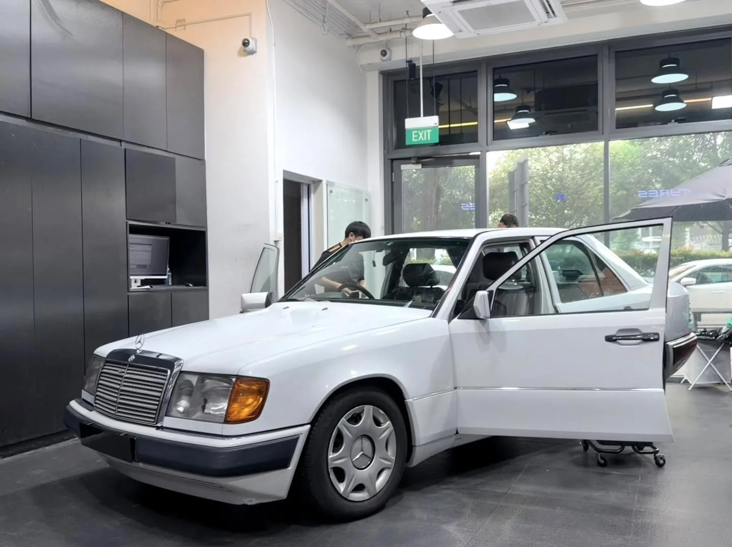 White Mercedes-Benz 200E with door open, technician inside applying film.