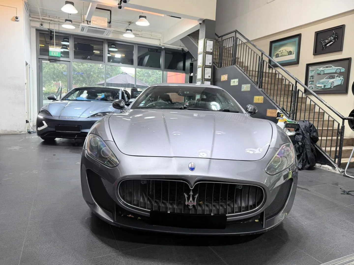 Silver Maserati GranTurismo convertible front view inside the workshop.