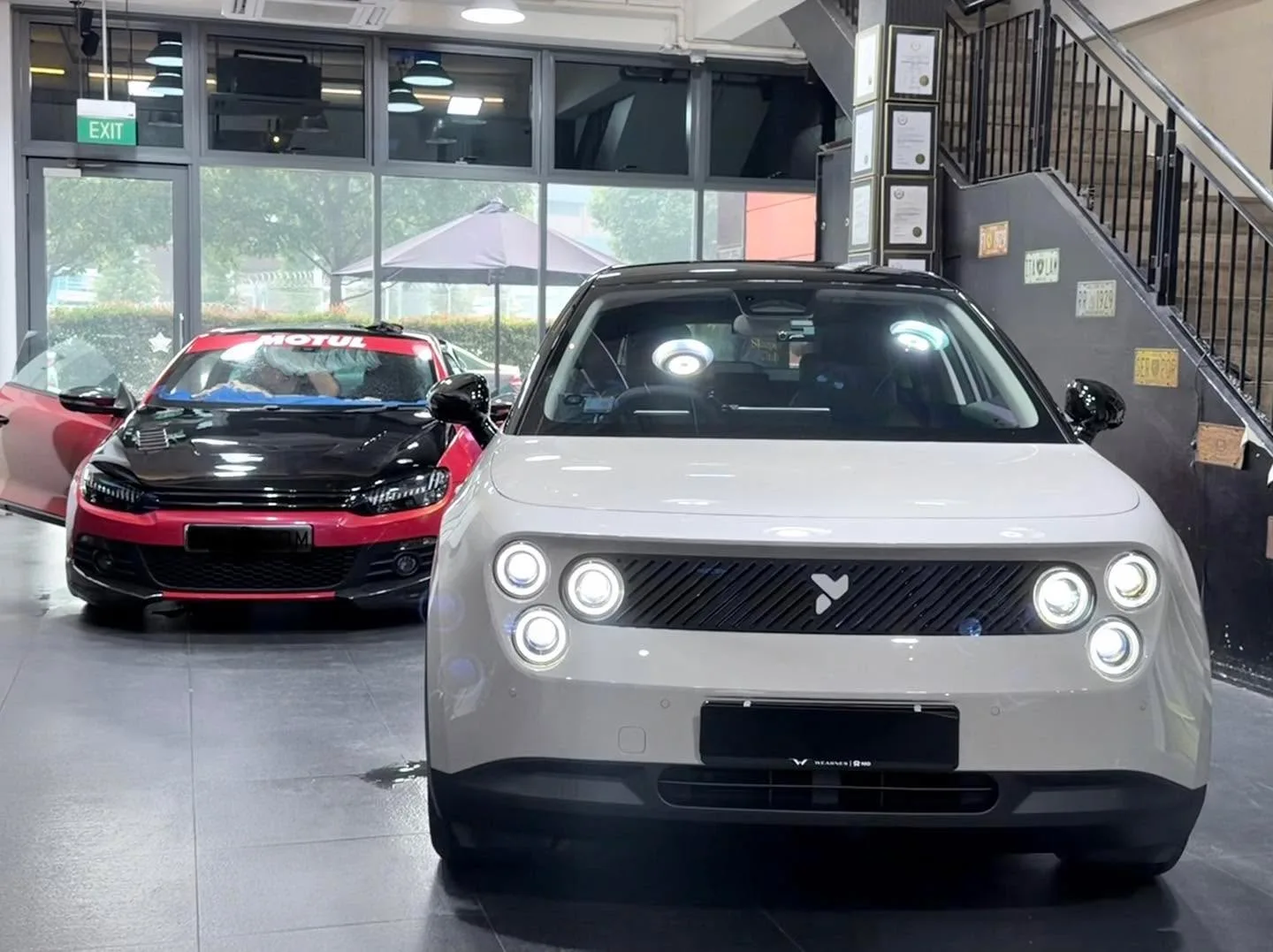 White Nio Firefly electric SUV facing forward in the workshop interior.