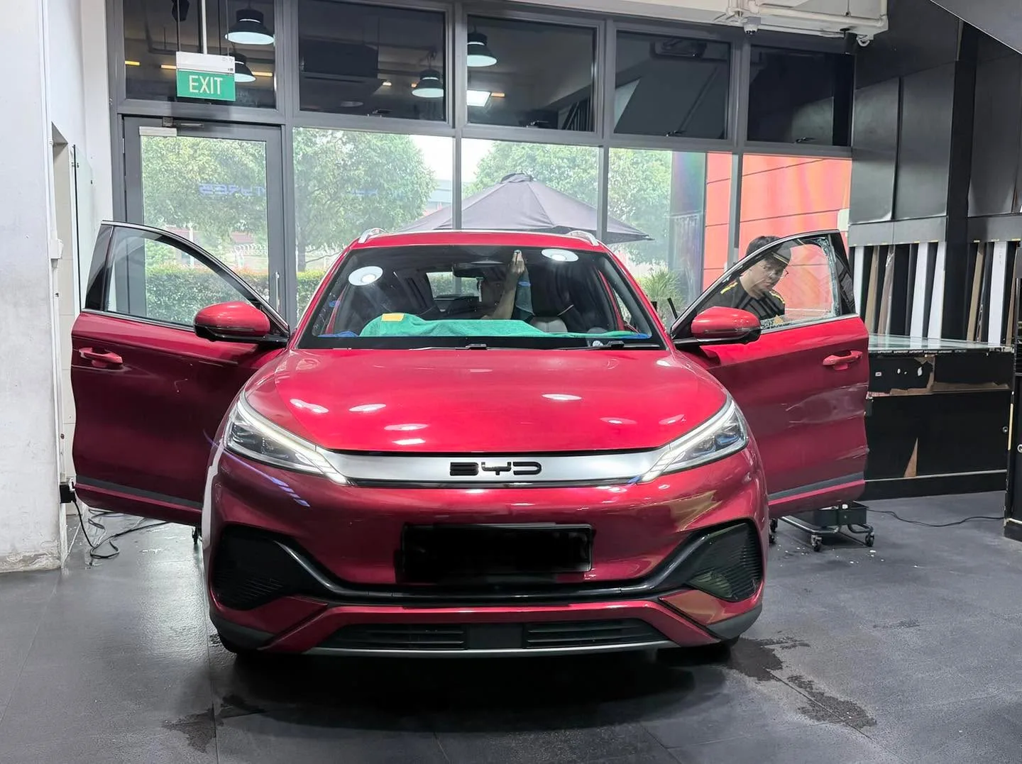 Burgundy BYD Seal SUV with doors open inside the workshop, viewed from front.