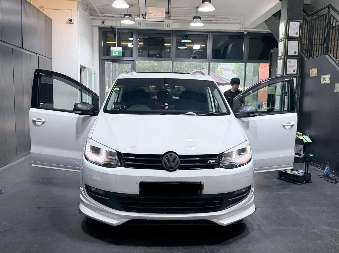 A white Volkswagen Sharan minivan with doors open, mid-tinting process in the workshop.