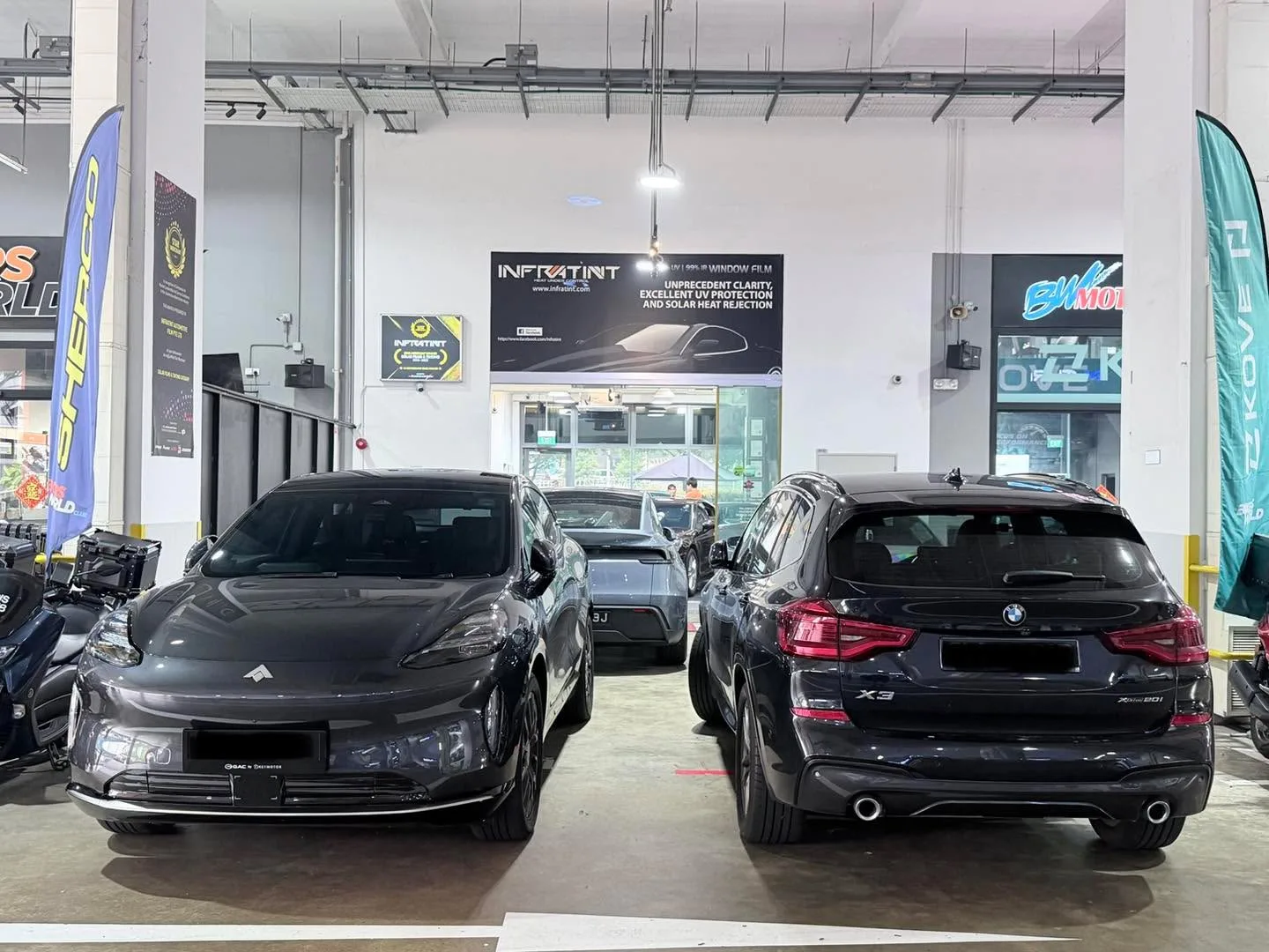 A black Citroën sedan and a black BMW X3 SUV stand side by side in the workshop.
