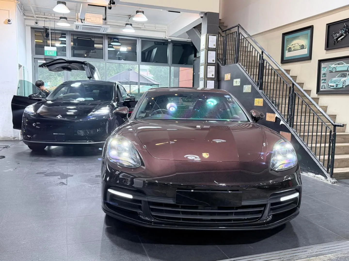 A dark burgundy Porsche sports car with white and blue tinted windows in the foreground.