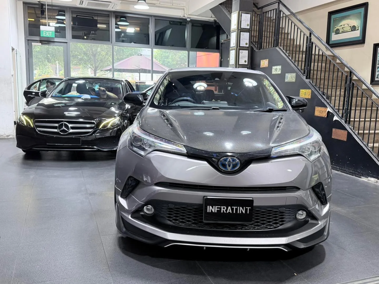 A silver Toyota CH-R and black Mercedes-Benz sedan in the workshop.