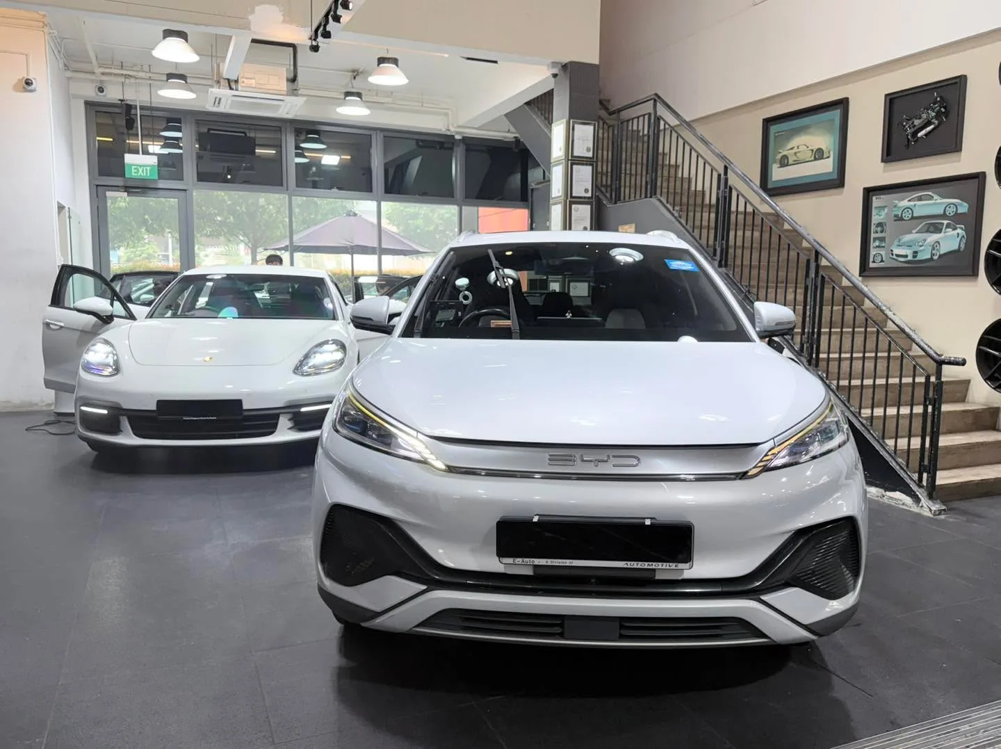 A white BYD Atto 3 SUV and white Tesla Model Y in the workshop.