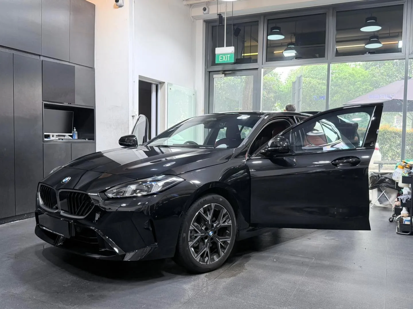 A black BMW sedan with driver door open in the workshop.