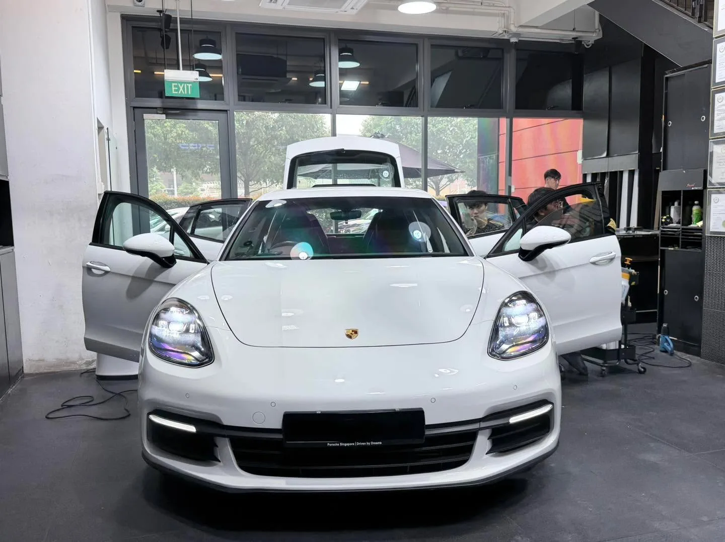 A white Porsche Cayman sports car with doors open.