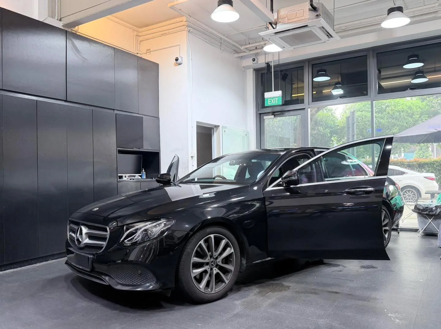 A black Mercedes-Benz sedan with door open in the workshop.