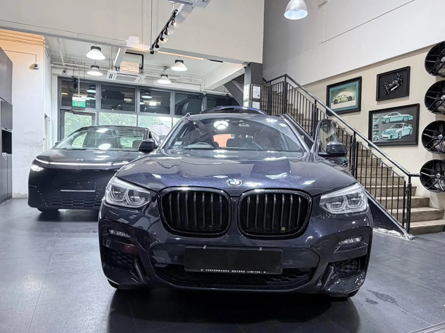 Dark blue BMW SUV with distinctive kidney grille facing camera in the workshop.