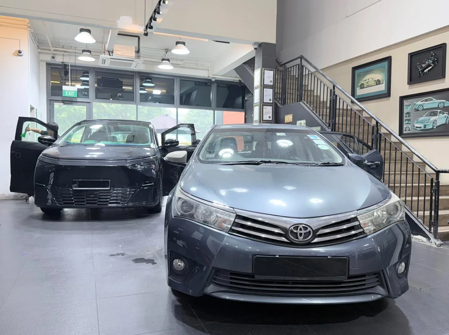 Grey Toyota sedan facing camera with doors open in the workshop.