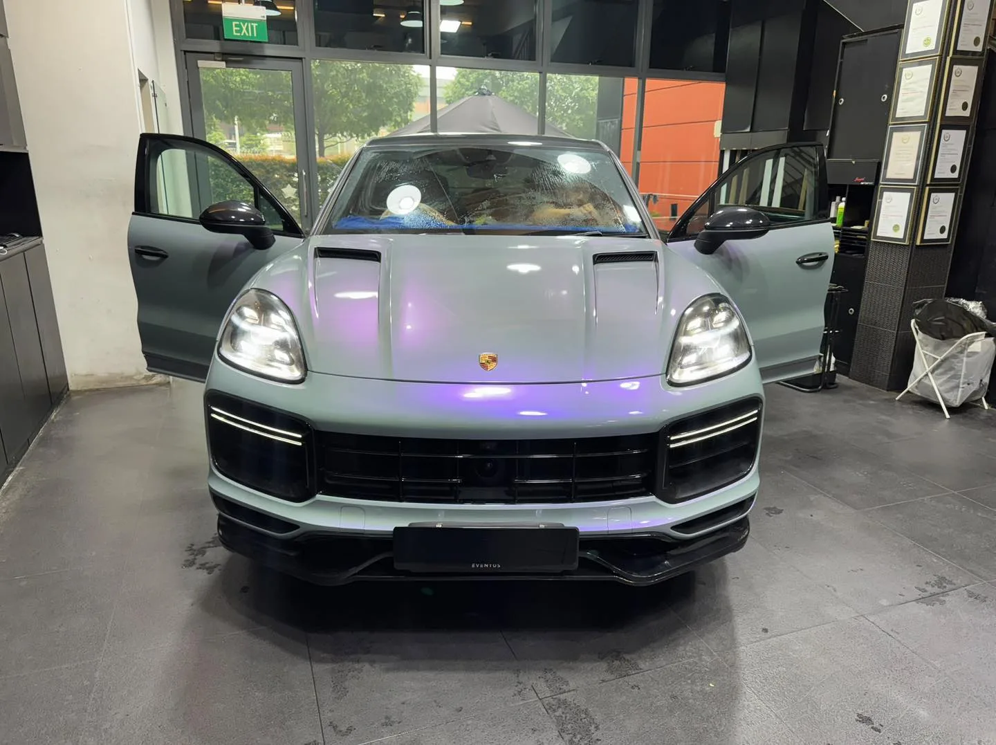 Pale blue Porsche Cayenne SUV with doors open in the workshop.