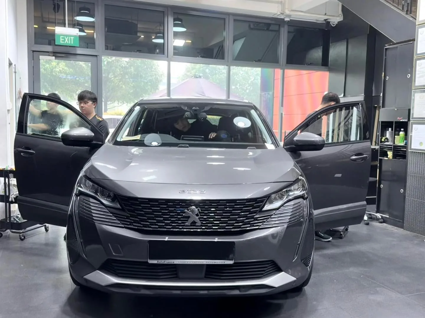 Silver Peugeot SUV with doors open in the workshop.