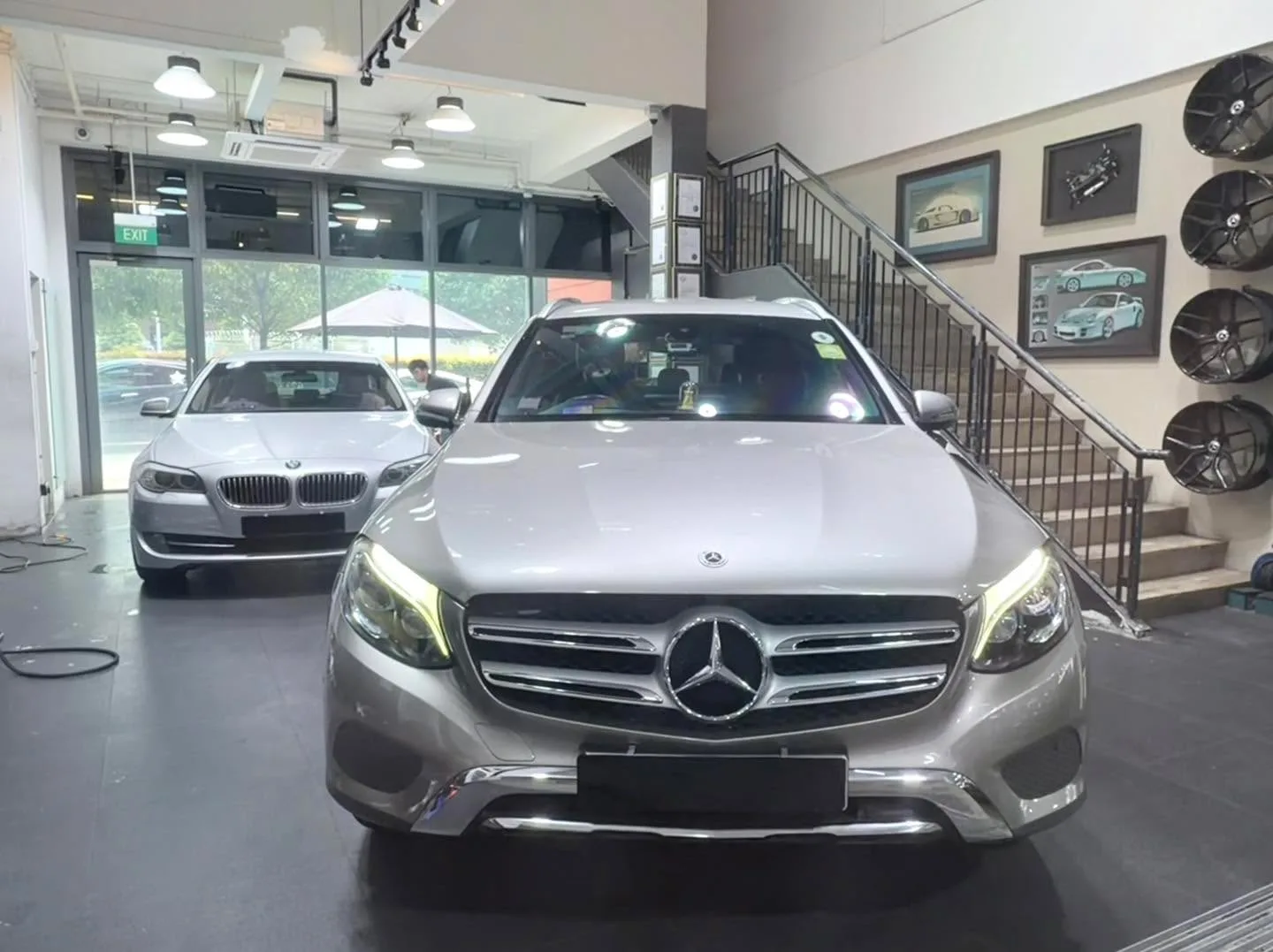 A black Mercedes-Benz C-Class in the foreground with other vehicles parked behind in the workshop.