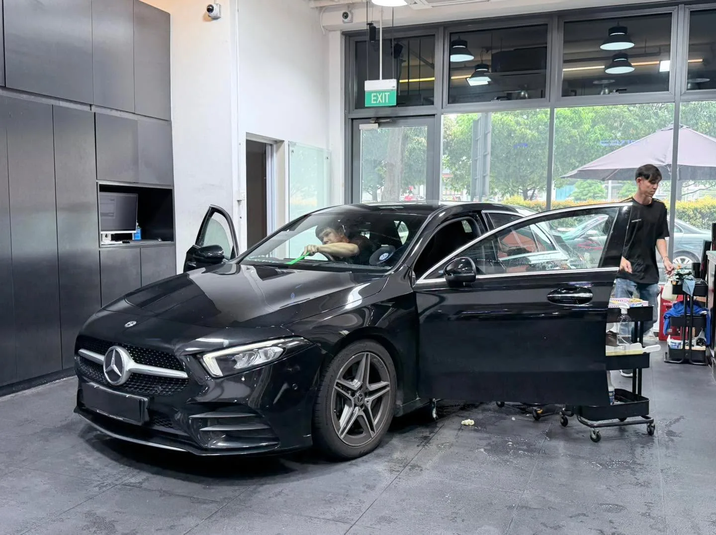 A white Volkswagen Golf hatchback viewed from the front with technicians working on it.
