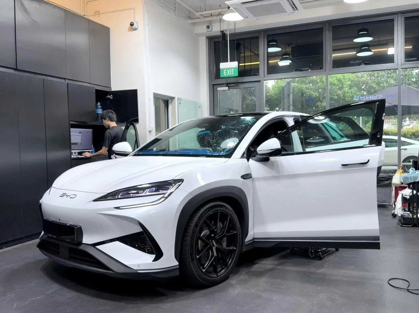 A white BYD Sealion 7 electric car with driver door open in the workshop.