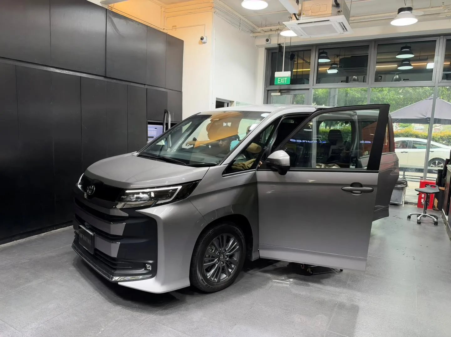 A silver Toyota Noah MPV with sliding door open in the workshop.