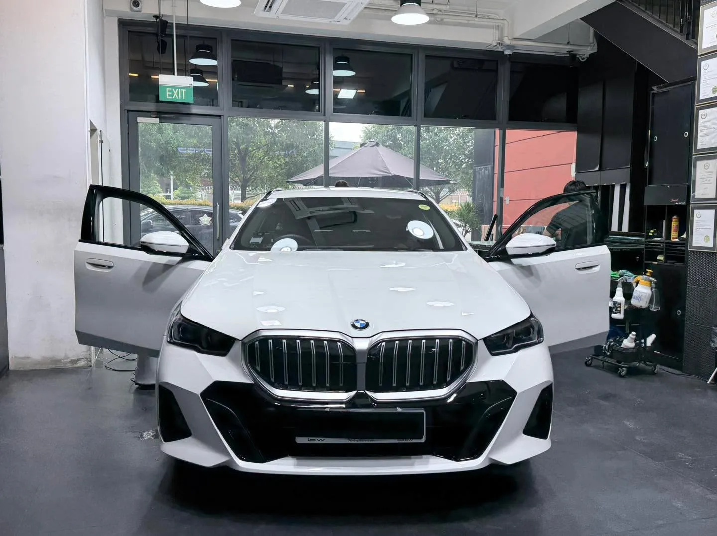 A white BMW compact car with doors open inside the workshop.